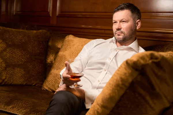 Szakállas Férfi Tölti Szabadidejét Egy Pohár Brandyvel Egyedül Kanapén Luxus — Stock Fotó