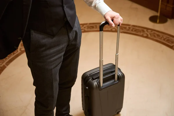 照片上的男人站在酒店大堂的黑色行李箱里 — 图库照片