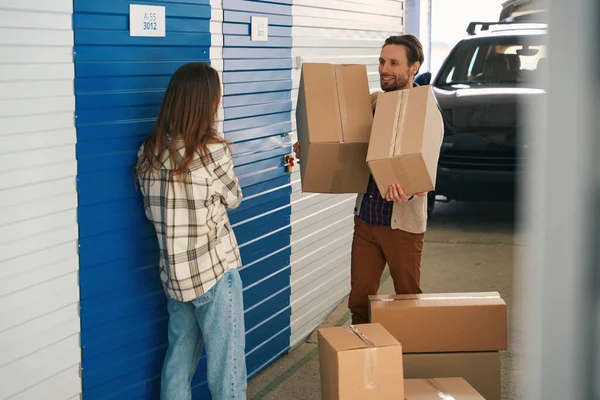 这对快乐的夫妇正在把纸板箱和其他东西放在仓库的自动储物柜里 — 图库照片