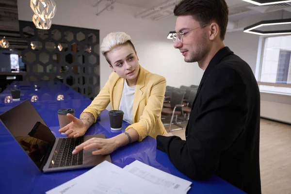 Bossy woman showing to new office worker how to work with data in special program, coworking space