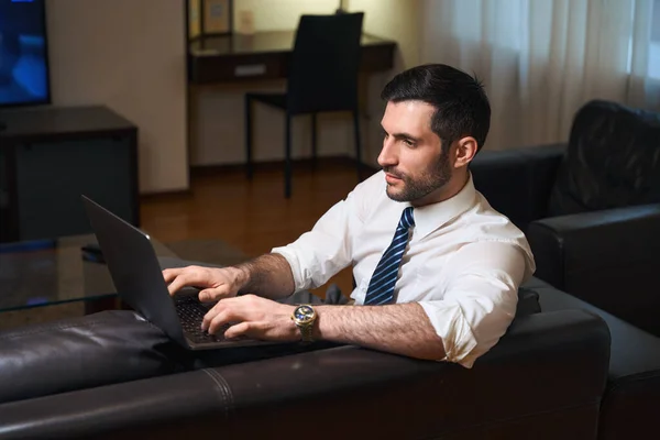 Businessman on a business trip works from a hotel room, he uses a laptop