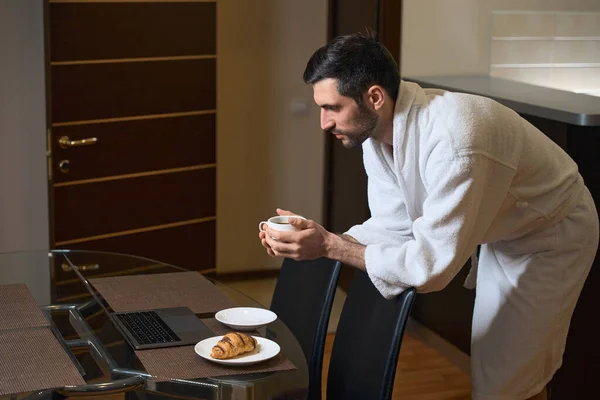 在厨房用餐区的笔记本电脑前 男人们都有咖啡和糕点 — 图库照片
