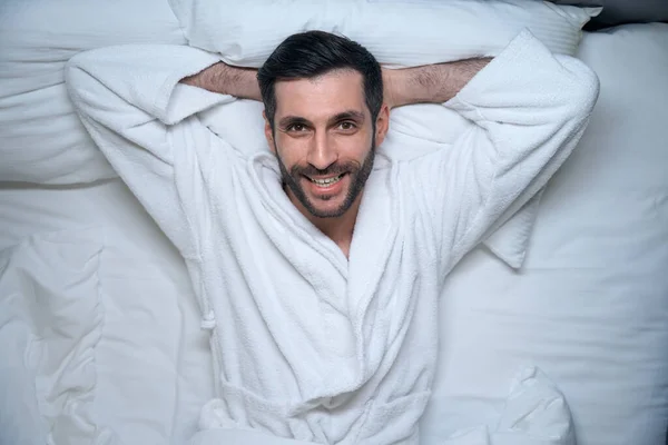 快乐的人躺在酒店房间的床上 穿着舒适的浴衣 — 图库照片