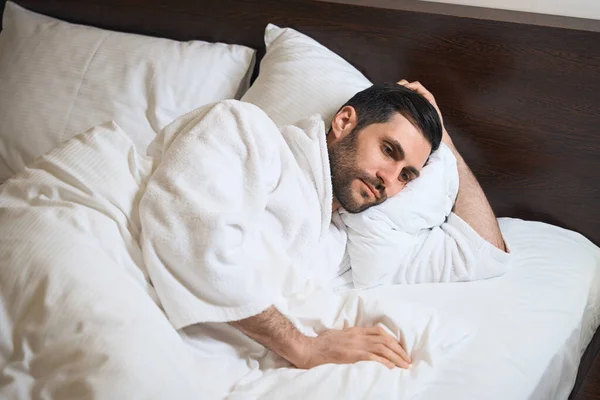 Κουρασμένος Φιλοξενούμενος Του Ξενοδοχείου Βρίσκεται Στο Κρεβάτι Μαλακά Μαξιλάρια Αυτός — Φωτογραφία Αρχείου