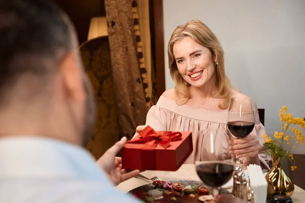 Volwassen Man Geeft Geschenkdoos Aan Mooie Dame Met Glas Wijn — Stockfoto