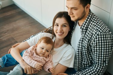 Neşeli anne ve baba mutfakta bebeğe sarılıyorlar. Uzaktan kumandalı iş aileyle iletişim kurmak için zaman kazandırıyor.