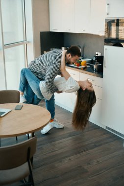 Mutlu genç eşler mutfakta tango yapar, rahat ev kıyafetleri giyen erkekler...