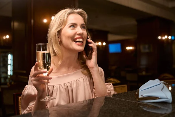 Sorrindo Mulher Bonita Falando Telefone Beber Vinho Espumante Enquanto Sentado — Fotografia de Stock