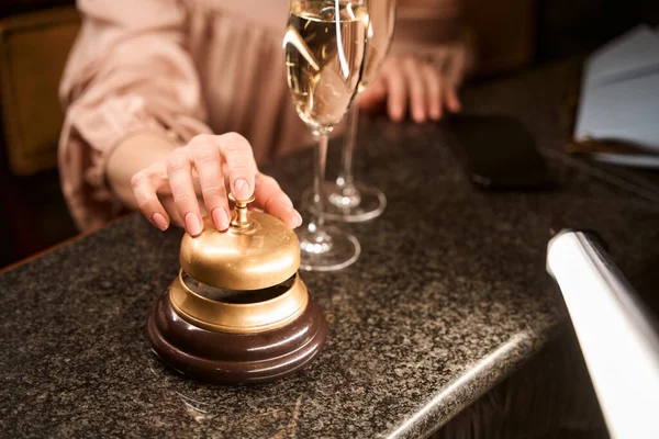 バーカウンターでワインのグラスの近くでサービスのための女性の手リンギング黄金の鐘の閉じる — ストック写真