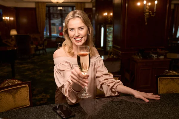 バーカウンターで一人で誕生日を祝いながら 輝くワインのガラスで乾杯する魅力的な女性 — ストック写真