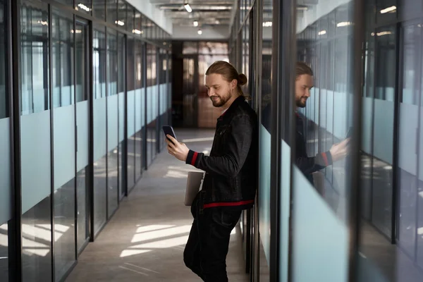 stock image Smiling male freelancer with notebook computer browsing mobile while standing indoors