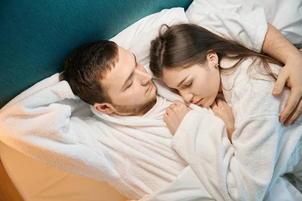 年轻的女人在一个留胡子的丈夫的怀里美美地睡着 这对夫妇睡在一张柔软的床上 — 图库照片