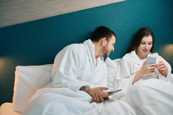 Smiling Man Peeking His Wifes Phone Couple Relaxing Soft Bed — Stock Photo, Image