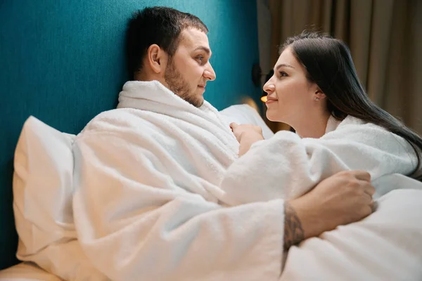 バスローブのカップルはお互いを美しく見て カップルは大きなベッドの上で贅沢 — ストック写真