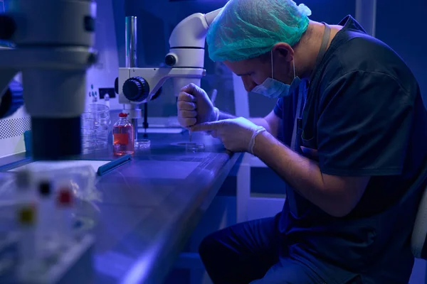 获得特许的化验室技术员 戴着无菌酶面具和手套 与胚胎一起工作 为更好地储存增加了特殊液体 — 图库照片