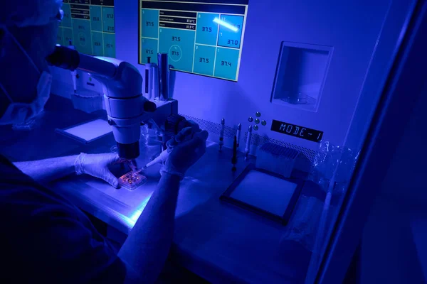 Pracownik Laboratoryjny Prowadzący Badania Płynów Pod Mikroskopem Kontrolujący Wskaźniki Monitorach — Zdjęcie stockowe