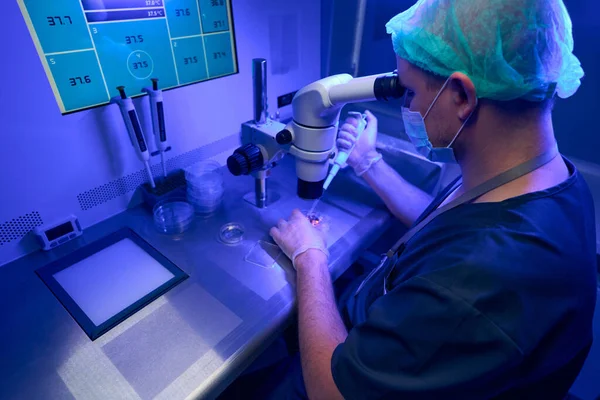 Laborante Guantes Estériles Mascarilla Protectora Mirando Microscopio Seleccionando Óvulos Sanos — Foto de Stock
