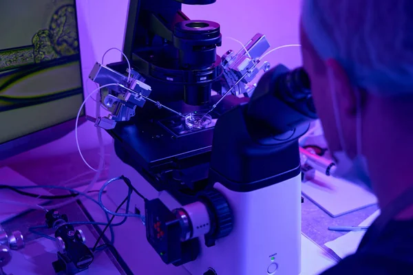 人类胚胎学家与微操作人员一起研究显微镜 进行胚胎活检以排除变异和异常 — 图库照片