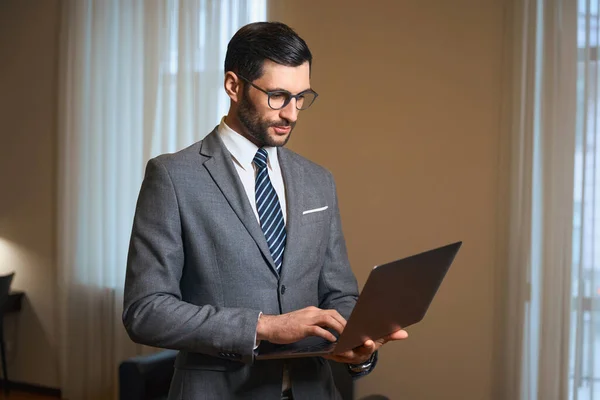 优雅的黑发女士站在酒店房间里 手里拿着笔记本电脑 一个男人穿着时髦的西服 — 图库照片