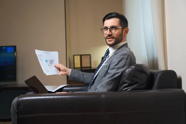 戴眼镜的中年男子正在一个放松的地方学习工作文件 他坐在一张舒适的椅子上 — 图库照片
