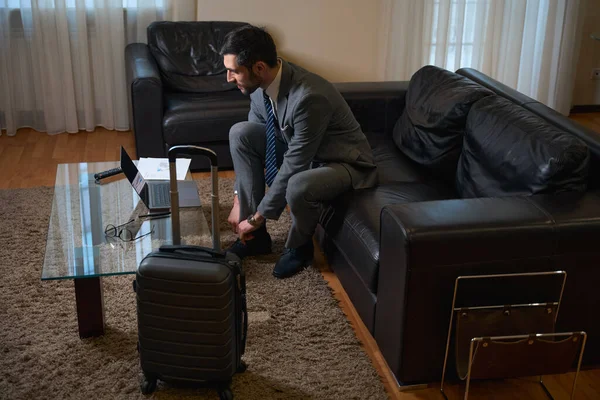 旅行中的男性会坐在宾馆房间里舒适的沙发上 通过笔记本电脑与人交流 — 图库照片