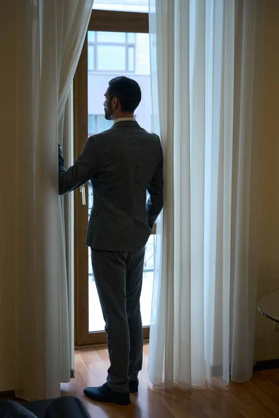 身穿西装的优雅男子站在法国窗口 男性则欣赏这一景象 — 图库照片