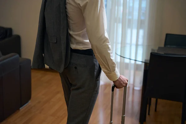 Traveling businessman stands in a hotel room with a travel suitcase, a man in a business suit