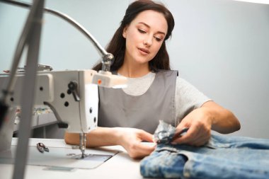 Kuru temizleme bürosu çalışanı, kuru temizleme işlemi sırasında düğmeleri ve süslemeleri kapatıyor.