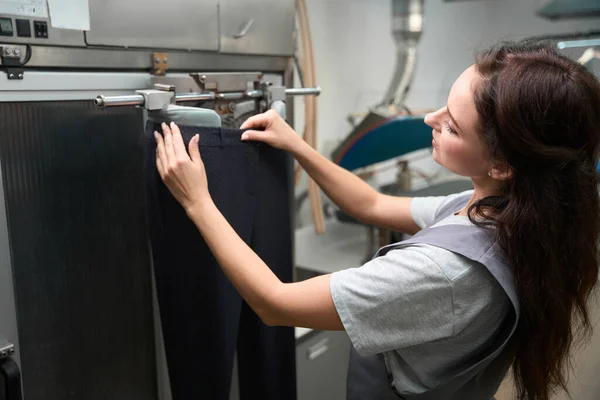 干洗服务操作员在自动熨烫壁炉架上穿裤子 洗后处理衣物 — 图库照片