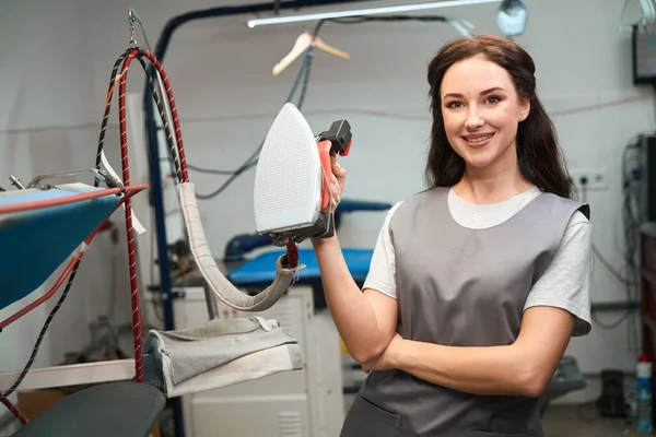 女性の洗濯業者は プロの鉄を保持笑みを浮かべて 高品質のドライクリーニングサービスで働く — ストック写真