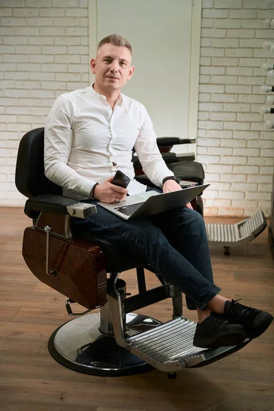 Homem Está Localizado Uma Cadeira Cabeleireiro Confortável Ele Usa Laptop — Fotografia de Stock