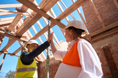 Pozitif inşaat mühendisleri birbirlerine beşlik çakarak inşaat alanında gelişen başarılı duvarları kutluyorlar.