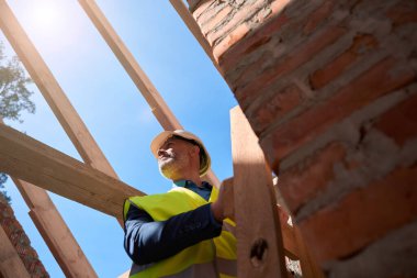 İnşaat alanındaki inşaat malzemelerinin kalitesini kontrol etmek için çelik yelek giyen erkek müfettiş, konut geliştirme