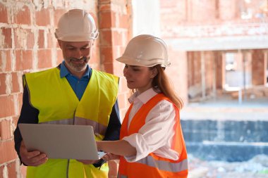 Dizüstü bilgisayarda şehir inşaatında erkek müteahhitlere gösterilen kadın mimar inşaat alanındaki ilerlemeden memnun mühendisler