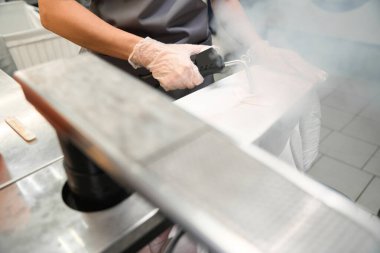 Kuru temizlemeci giysileri buharla tedavi ediyor, lekeleri çıkarıyor ve katları dikkatlice ütülüyor.