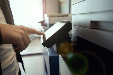 Çalışan, birlikte çalışma alanında bir fotokopi makinesi kullanır, modern ofis ekipmanları kapalı alandadır.