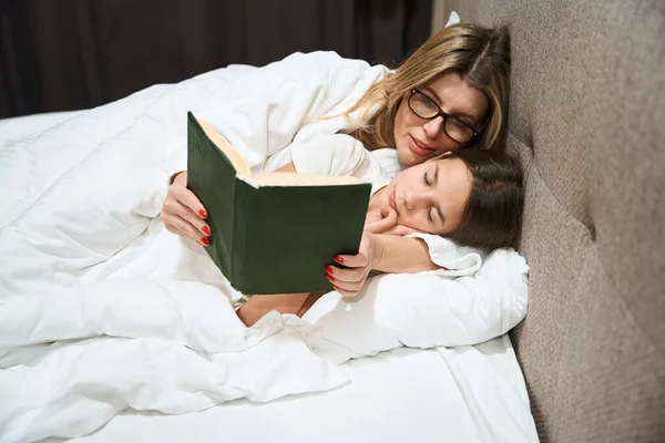 Woman Glasses Lying Sleeping Daughter Looking Book Hotel Room — Stock Photo, Image