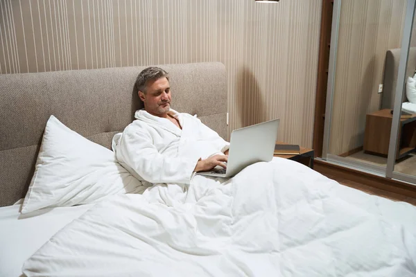 Bărbat Haină Albă Odihnindu Pat Lucrând Laptop Camera Hotel — Fotografie, imagine de stoc