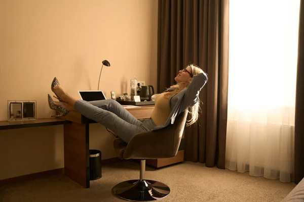 穿着眼镜和西装的微笑女人坐在椅子上 在酒店房间里放松 — 图库照片