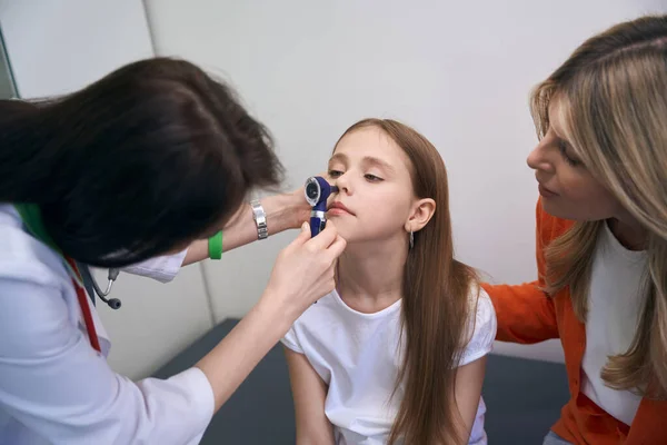 専門的なツールを使用して小さな女の子の鼻をチェックする喉科医のケア 専門的な医療検査と相談 — ストック写真