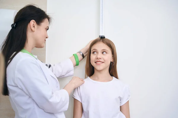 小児科医は特別なツールで女の子の高さを測定します 学年前の生徒の健康診断 子供のリハビリテーション — ストック写真