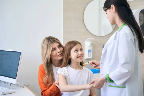 Vänlig Kvinna Pediatriker Ger Termometer Till Liten Flicka Sitter Mammor — Stockfoto