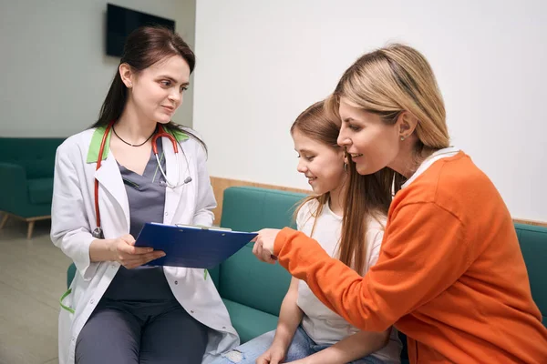 笑顔の女性小児科医は 小さな女の子のテスト結果を共有し 母親とデータを話し合い 問題を診断し 薬を処方する — ストック写真