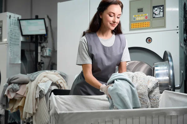 洗濯屋の女性労働者は ソートされた衣類 ドライクリーニングサービスと産業用洗濯機をロード — ストック写真