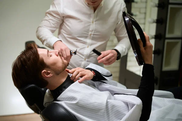 Young Man Sits Chair Barbershop Looks Mirror Consulted Master Barber — Stock Photo, Image