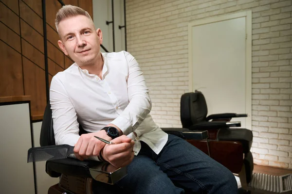 Barber Blonde Sits Professional Chair Has Scissors Comb His Hands — Stock Photo, Image