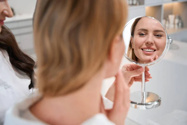 幸せな女性のブロンドは 美容師との協議で鏡を見て 彼女は鏡の中の反射に満足しています — ストック写真