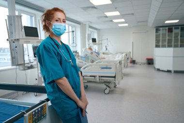 General doctor wearing the medical face mask and standing in the reanimation ward clipart