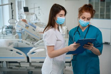 Klinikte analiz panosu tutarken birinin teşhisini analiz eden odaklanmış doktorlar.