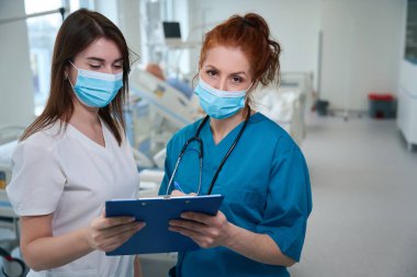 Hastane odasındaki ameliyattan sonra başhekim hastaların durumlarını hemşirelerle tartışıyor.